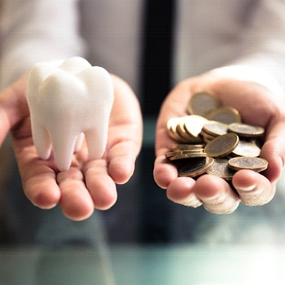 hand holding tooth and coins representing cost of cosmetic dentistry in Rancho Bernardo