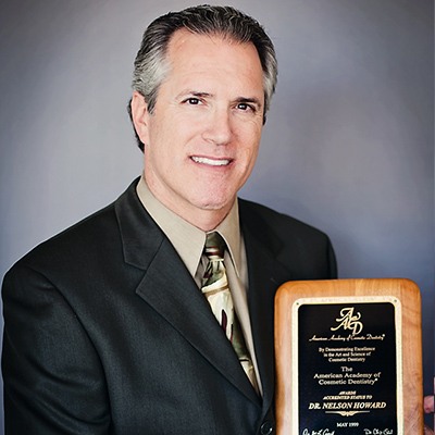 Doctor Howard holding his American Academy of Cosmetic Dentistry accreditation plaque