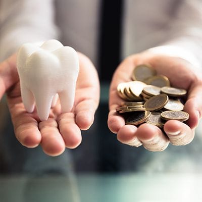 Person holding out model atooth and coins