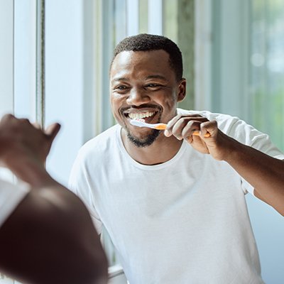 Man in white shirt brushing his teeth