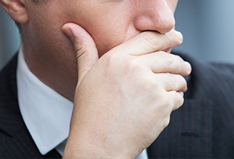 Man with lost filling covering his mouth