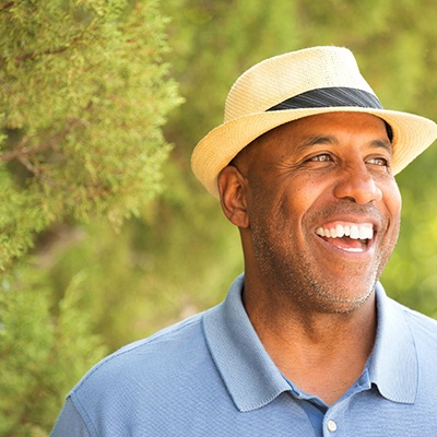 man in a blue polo shirt standing in front of trees 