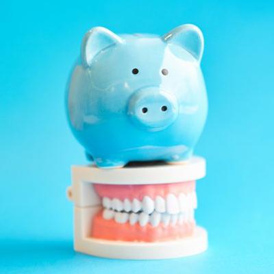 blue piggy bank sitting on top of a set of full dentures 