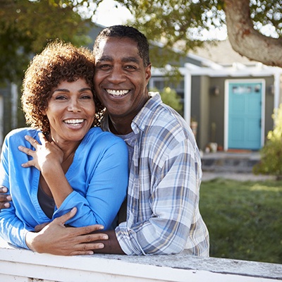 happy couple standing in their front yard 