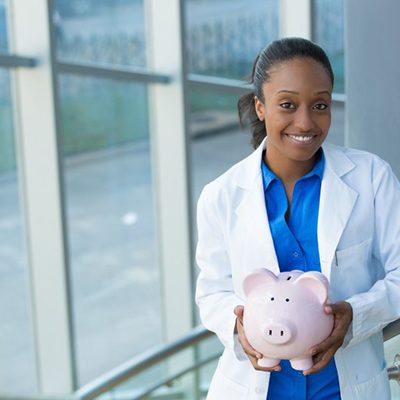 smiling dentist holding a pink piggy bank 