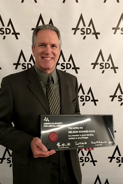Doctor Howard holding a plaque from the American Society for Dental Aesthetics