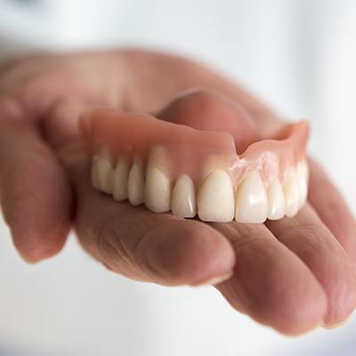 Hand holding a set of full dentures