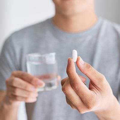 Man holding pill and glass of water