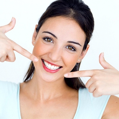 A woman pointing at her smile.