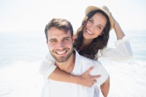 couple smiling on the beach after seeing their cosmetic dentist 