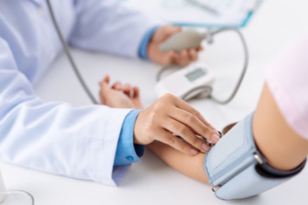 Dentist taking blood pressure of patient.