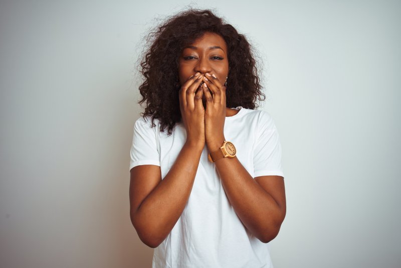 a woman covering her cosmetic dental flaws in Rancho Bernardo