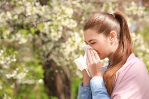 a woman blowing her nose during allergy season