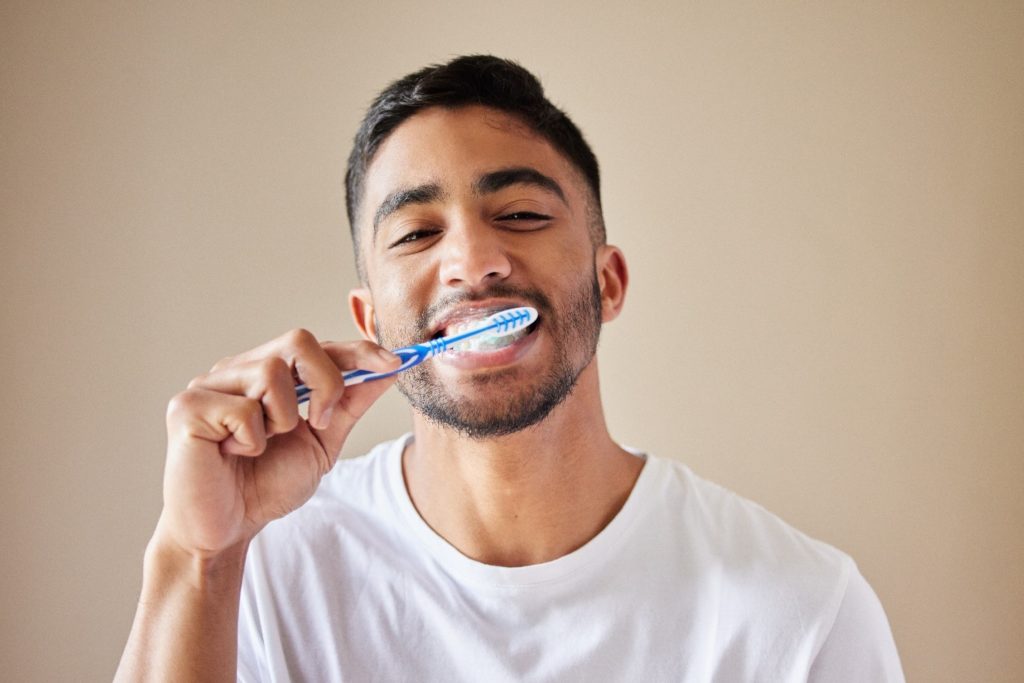 person using toothpaste for veneers to brush teeth