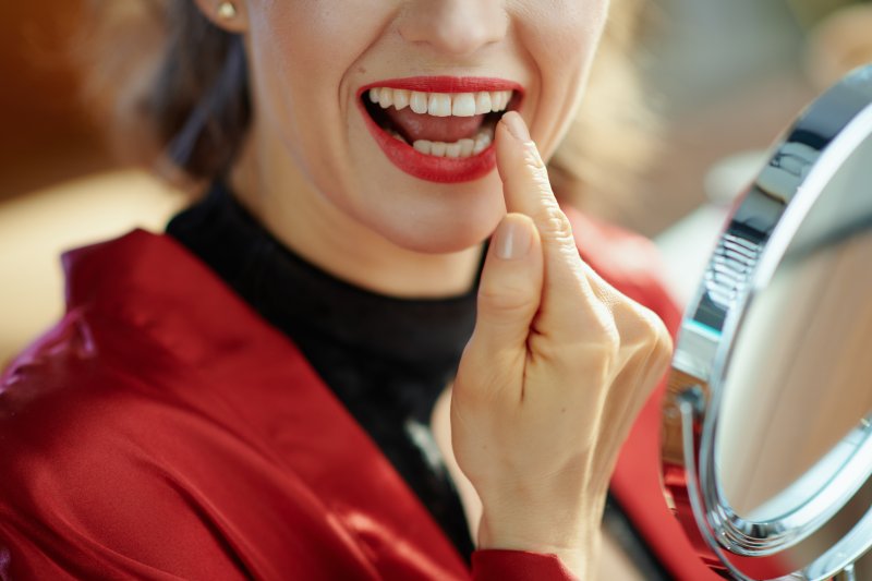 Woman smiling and looking at her teeth after whitening treatments