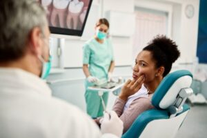 Patient holding mouth in dentist's chair.