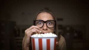 Woman watching a scary movie eating popcorn
