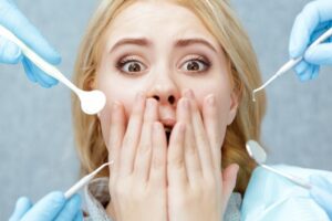 Patient in dentist's chair with scared facial expression.
