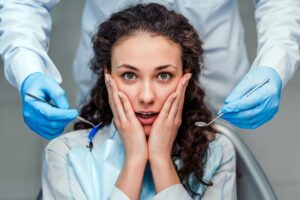 Patient holding hands to face from nervousness in dentist's chair.
